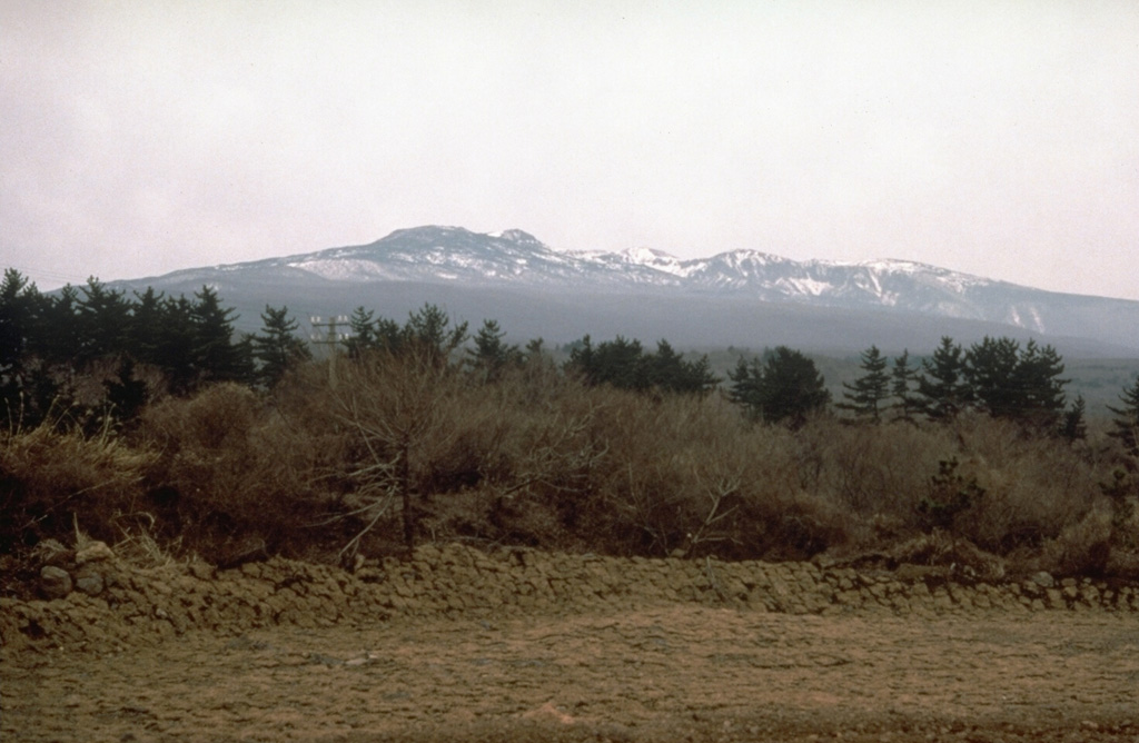 The massive Halla shield volcano, seen here from the south, forms much of the 40 x 80 km Cheju Island, which lies 90 km S of the Korean Peninsula. More than 360 late-Pleistocene and Holocene basaltic cones on the flanks of the low-angle volcano were erupted primarily along the long axis of the NE-SW-trending island. Most of these are scoria cones, but about 10 along the coast are Pleistocene tuff rings and tuff cones. Flank eruptions continued into historical time, with the final two taking place during the 11th century. Photo by Norm Banks, 1980 (U.S. Geological Survey).