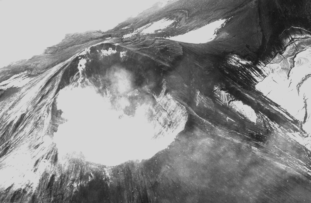 The Kanaga summit crater of is seen here in 1942. Both explosive and effusive eruptions have been recorded, and in 1906 lava flows reached the sea along the SW coast. In 1994 lava flows reached the NW coast. Kanaga is constructed within the Kanaton caldera. Photo by R. Katchadoorian, 1942 (from the collection of Maurice and Katia Krafft).