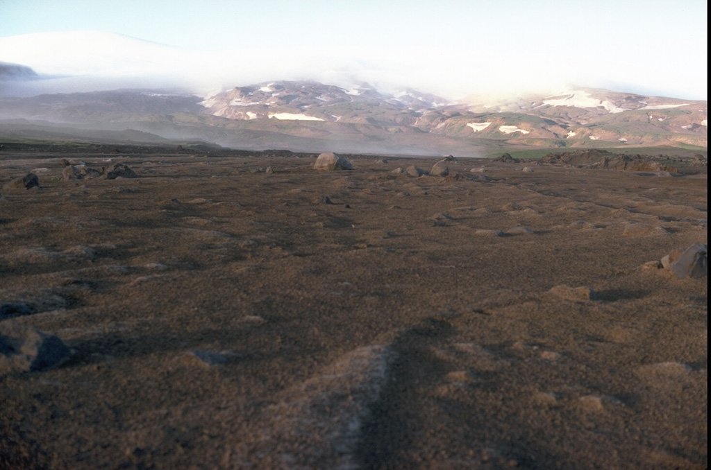 A lahar produced by the melting of snow and ice during a February 4-9, 1978 eruption of Westdahl volcano in the Aleutians is seen in the foreground of this summer 1978 photo taken near Scotch Cap on the SW coast.  The lahar traveled 12 km from the summit, visible at the upper left.  The 1978 eruption blasted a 1.5-km wide, 500-m deep crater through the summit icecap. Copyrighted photo by Katia and Maurice Krafft, 1978.