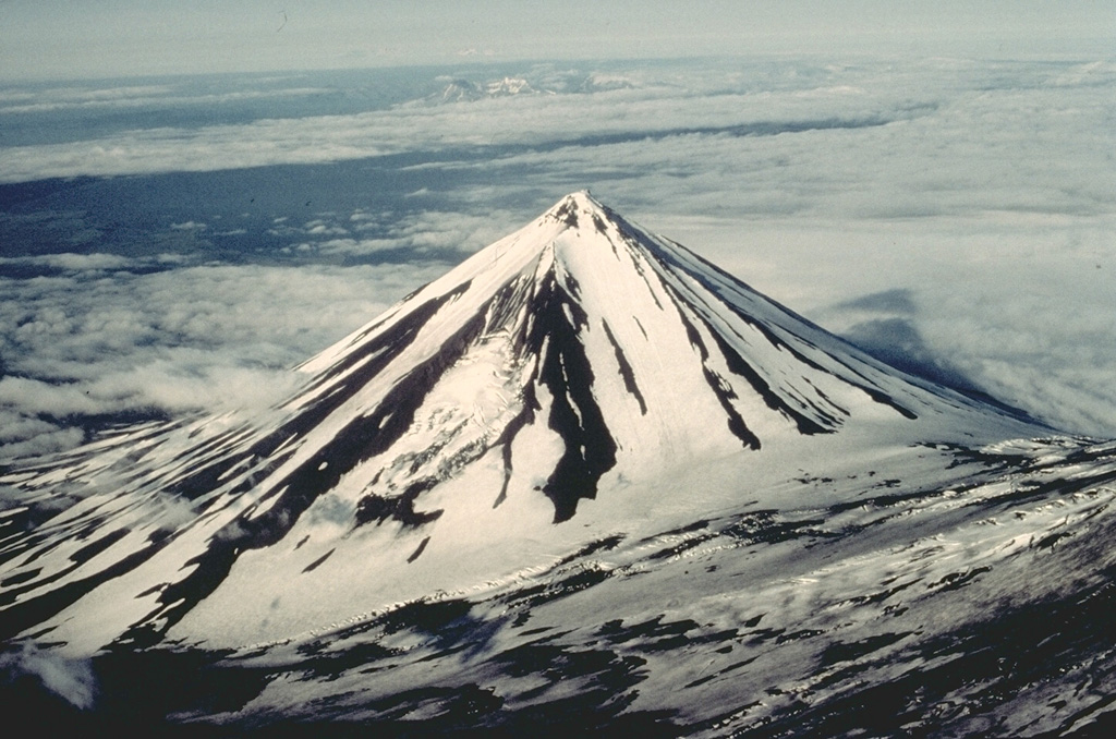 Pavlof Sister is a symmetrical stratovolcano that forms a twin volcano with Pavlof volcano, whose lower flank forms the slope at the lower right in this view from the SW.  Despite its youthful profile, Pavlof Sister has had only one historical eruption, which began in 1762.  Glacial dissection has produced a series of parasol-ribbed ridges that radiate from the 2142-m, sharp-peaked summit.   Copyrighted photo by Katia and Maurice Krafft, 1978.