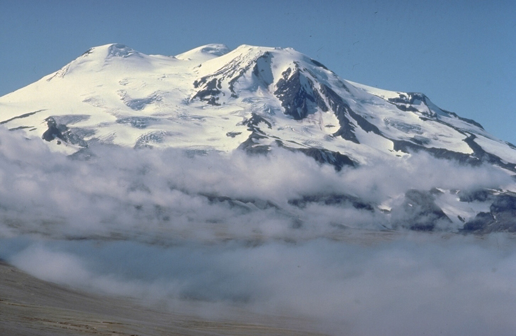 Glacier-covered Mount Mageik, seen here from the north, is a broad stratovolcano that is the SW-most of a group of volcanoes encircling Novarupta volcano.  Despite its extensive glacial cover, it is only moderately dissected, and most of its exposed lava flows are of Holocene age.  Its elongated summit contains four knobs that were spatter and lava-flow vents.  Reports of historical eruptions during the 20th century are of variable certainty.   Copyrighted photo by Katia and Maurice Krafft, 1978.