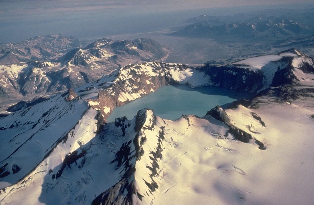 Alaska's lake-filled Katmai caldera, seen here from the SE, collapsed during a catastrophic eruption in 1912 of Novarupta volcano, hidden behind the far caldera wall 10 km to the west.  Little tephra was erupted from Katmai itself, but Novarupta produced the Valley of Ten Thousand Smokes ash flow, whose deposits form the broad flat valley in the right distance.  Prior to 1912, Mount Katmai was a 2290-m-high complex of 4 small stratovolcanoes, similar to Trident volcano to the SW. Copyrighted photo by Katia and Maurice Krafft, 1978.
