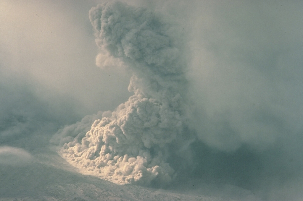 Near the end of the 1986 eruption, during August 19-31, summit lava dome growth was renewed and pyroclastic flows were again produced by collapse of the dome.  This August 28 photo shows a pyroclastic flow descending the north flank of Augustine out of a cloud bank that obscures the summit.  These pyroclastic flows were smaller than those earlier in the 1986 eruption, which had reached the north coast of the island. Copyrighted photo by Katia and Maurice Krafft, 1986.