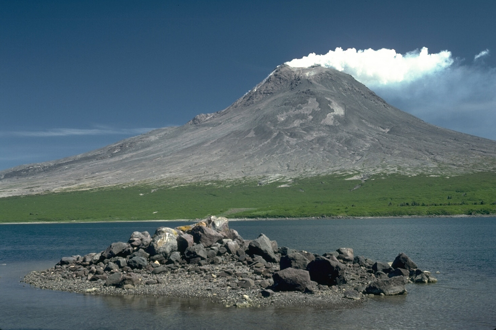 In the foreground is a hummock of a debris avalanche deposit produced by collapse of the Augustine summit about 450 years ago. The avalanche swept into Kamishak Bay and traveled a distance of 11 km from the summit, forming the 2 x 3 km wide West Island. The fine-grained component of this avalanche hummock has been removed by the powerful Cook Inlet tides. The eruption was accompanied by a small lateral blast. Photo by Lee Siebert, 1987 (Smithsonian Institution).