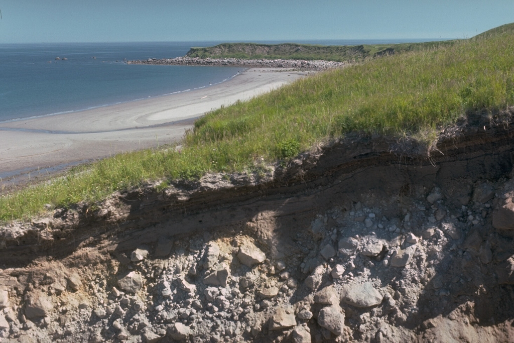 The recent history of Augustine has been characterized by repetitive collapse of the summit area, producing debris avalanches that often reached the sea on all sides of the island, forming rocky deposits. This gully near the east shoreline exposes one such debris avalanche deposit. The Northeast Point debris avalanche deposit forms the headland in the distance. Photo by Lee Siebert, 1990 (Smithsonian Institution).