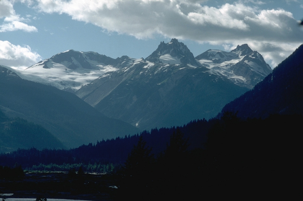 Mount Capricorn, Meager Mountain, and Plinth Mountain (left to right) are seen above the Lillooet River valley to the SE. They are three of the eight volcanic centers forming the Tertiary to Holocene Meager volcanic complex. Deep glacial erosion has exposed the interior of a group of dissected rhyodacite volcanic remnants that form the highest peaks. Photo by Lee Siebert, 1987 (Smithsonian Institution).