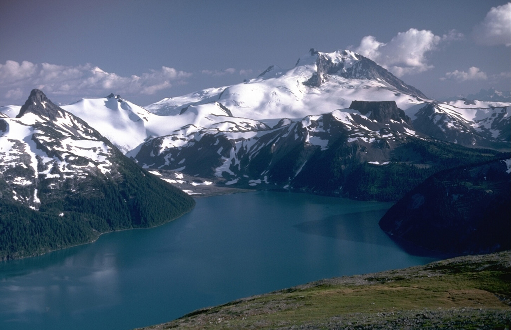 Mount Garibaldi, rising above Garibaldi Lake to the north, is a largely Pleistocene stratovolcano with a summit lava dome complex. The volcano was partially constructed over the Cordilleran ice sheet and contains many ice-contact features. Its final eruptions during the early Holocene included lava flows that mantled the western landside scarp and a massive lava flow from Opal Cone, a SE flank vent, that traveled 20 km to the south and west. Photo by Lee Siebert, 1983 (Smithsonian Institution).