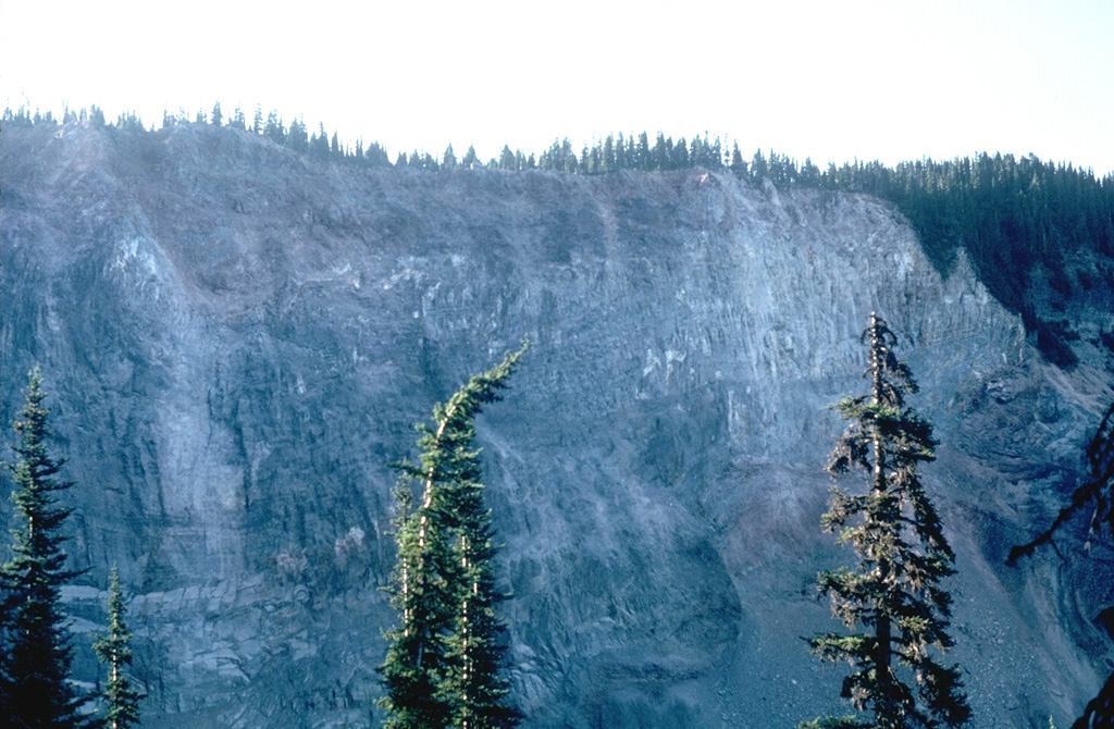 The cliff along Rubble Creek is the margin of the early Holocene lava flows that formed Garibaldi Lake. The steep lava flow margin formed when the flow ponded against the retreating continental glacier filling the Cheakamus River valley. This has been the source of several landslides down Rubble Creek, leaving a scarp known as The Barrier. Photo by Lee Siebert, 1983 (Smithsonian Institution).