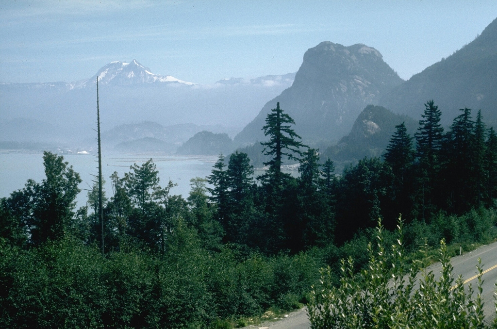 Mount Garibaldi rises above Howe Sound, 80 km N of Vancouver. The steep-sided peak on the right is the Squamish Chief, a glacially eroded peak of the Coast Range batholith. Garibaldi was constructed during the Pleistocene, partially overriding the Cordilleran ice sheet. Retreat of the ice sheet left the western side of the volcano unsupported, causing many landslides into the Cheakamus River valley. Photo by Lee Siebert, 1976 (Smithsonian Institution).