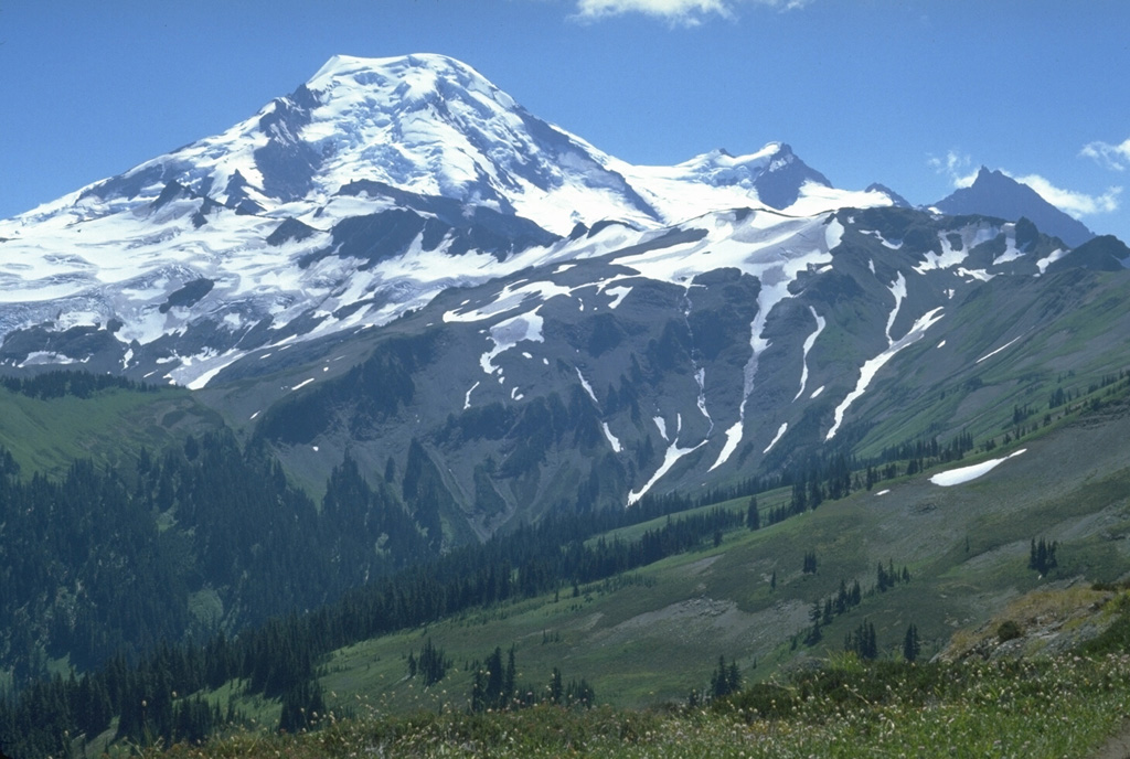 The north flank of Mount Baker is seen from Skyline Divide with the two peaks of the Pleistocene Black Buttes on the right horizon. Chowder Ridge extends across the middle of the image in front of Black Buttes towards Mt. Hadley, the peak below the flat-topped Mount Baker summit. The ridge is named for its marine brachiopod fossils and contains numerous dikes, the feeders for a large early and mid-Pleistocene volcanic center that has been almost entirely eroded away by Pleistocene continental ice sheets. Photo by Lee Siebert, 1979 (Smithsonian Institution).