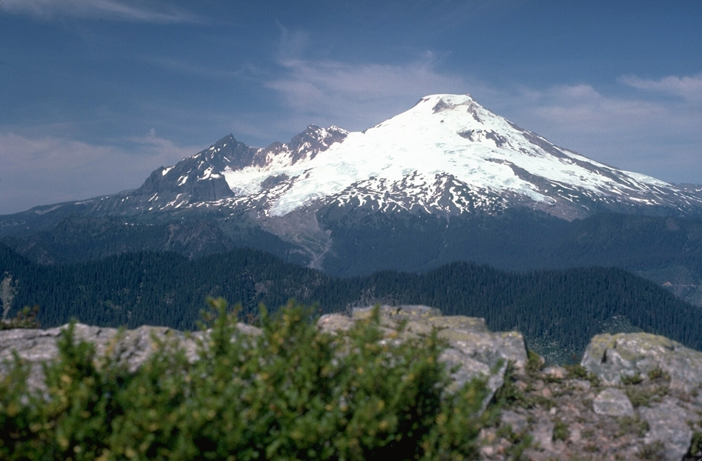 Mount Baker in the northern Cascades rises 1,500 m above a dissected basement complex of metamorphic and sedimentary rocks, exposed at Dock Butte in the foreground. On the left skyline is the glacially eroded core of the Pleistocene Black Buttes stratovolcano, a predecessor to Mount Baker. From left to right, the Deming, Easton, Squock, Talum, Boulder, and Park Glaciers drape the volcano's flanks. Photo by Lee Siebert, 1990 (Smithsonian Institution).