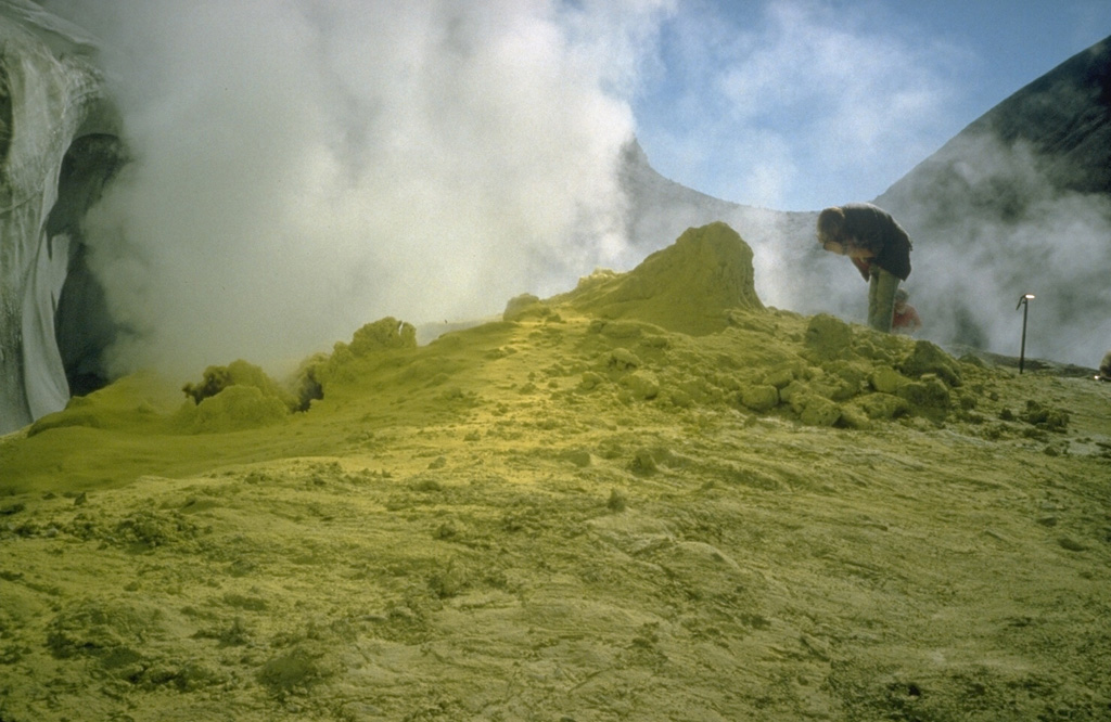 A geologist examines a fumarole surrounded by sulfur mineralization at Sherman Crater in 1981. Greatly increased thermal emission beginning in 1975 melted glacial ice in Sherman Crater and created many new fumaroles. Plumes are occasionally visible from the Puget lowlands. Photo by Bill Chadwick, 1981 (U.S. Geological Survey).
