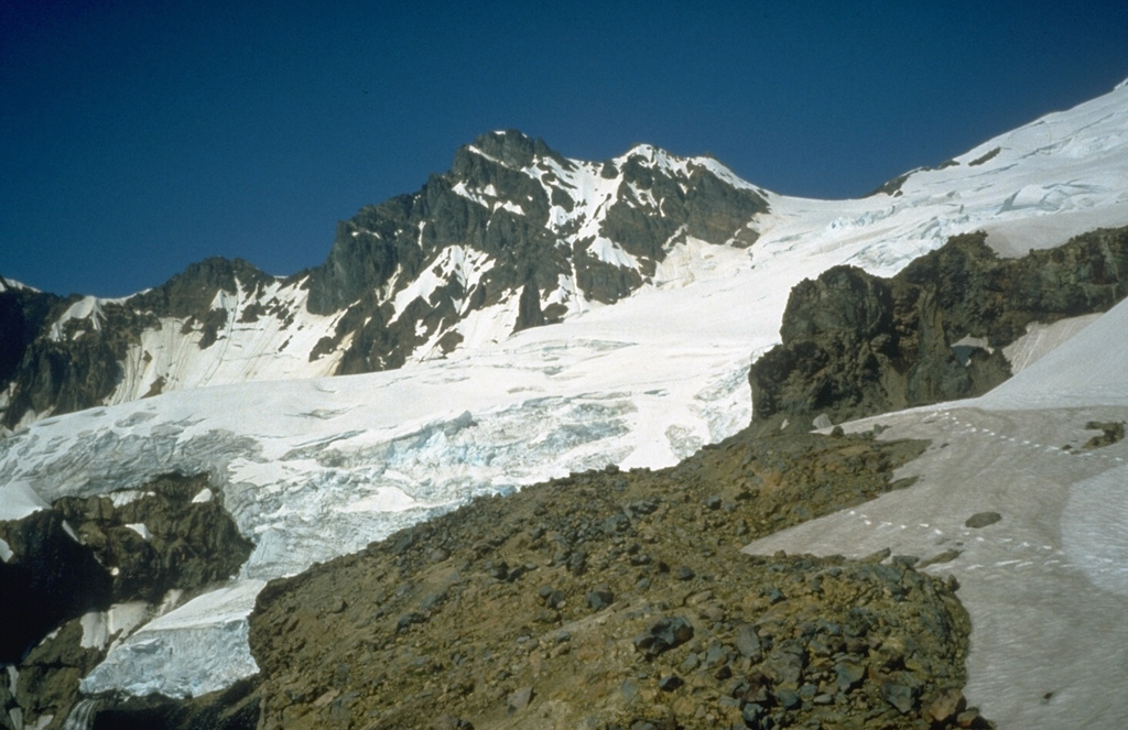 Colfax Peak (center) is an erosional remnant of Black Buttes volcano, a predecessor to Mount Baker that was active from about 500,000 to 300,000 years ago. Coleman Saddle (right center) divides the NE-dipping lavas of Black Buttes from Mount Baker, whose summit lies out of view to the upper right. Easton Glacier descends diagonally across the photo to the SW. Photo by Bill Chadwick, 1981 (U.S. Geological Survey).