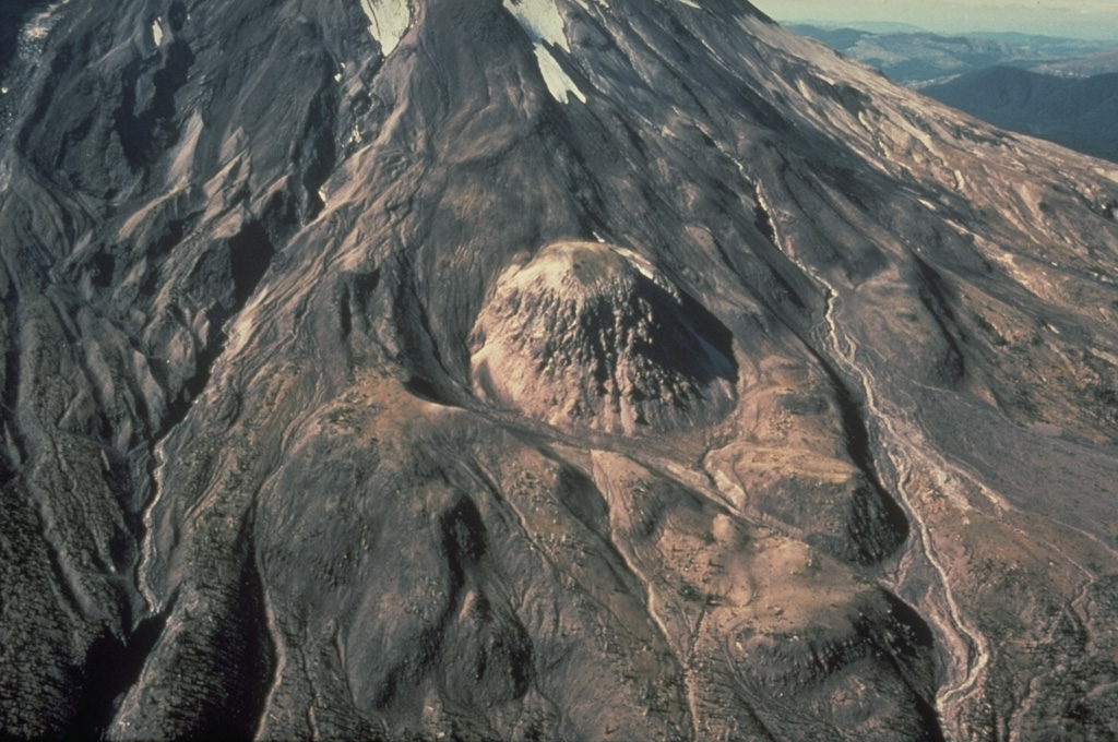 East Dome, the small lava dome at the center, is seen in this 1978 aerial photograph. An explosive eruption preceded emplacement of the dome on the lower E flank of Mount St. Helens about 1,800 years ago. Both the tephra deposit and the lava dome are of a hypersthene dacite composition unique to Mount St. Helens products. This eruption was part of the Sugar Bowl Eruptive Period. Photo by Rick Hoblitt, 1978 (U.S. Geological Survey).