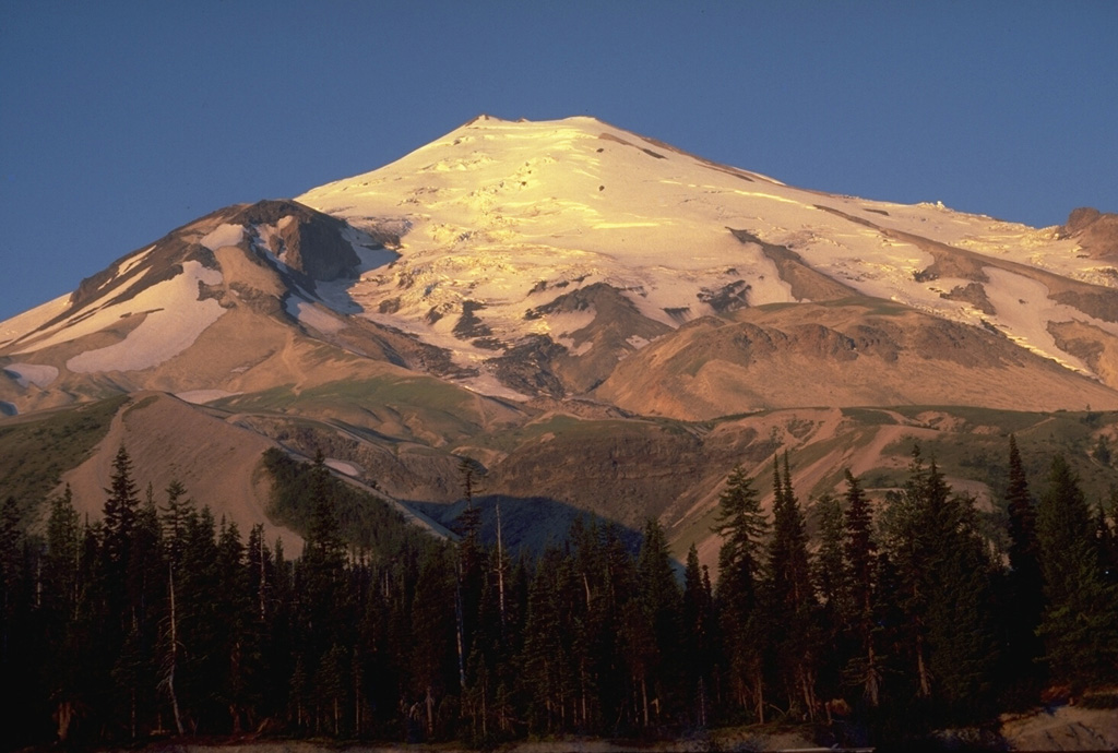 Four lava domes are visible in this 1979 photo from Timberline parking lot on the N flank of Mount St. Helens. In addition to the glacier-covered summit lava dome, the Dogs Head lava dome is the prominent mound on the left skyline, the Sugar Bowl lava dome is the flat mound below the glaciers to the right, and the 19th-century Goat Rocks dome (removed by the 1980 eruption) is to the far right. Photo by Lee Siebert, 1979 (Smithsonian Institution).