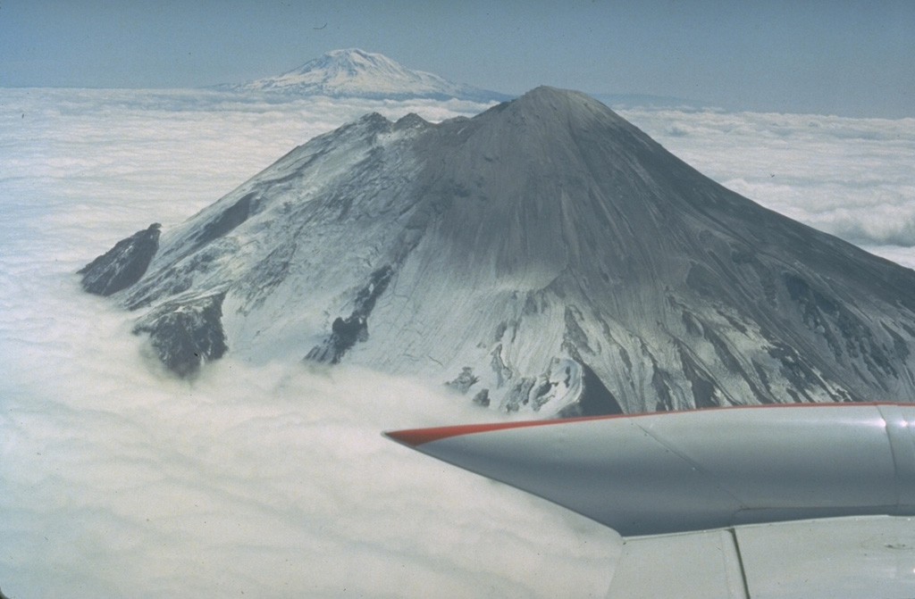 This 16 May 1980 photo, taken two days before the catastrophic eruption, shows Mount St. Helens from the west with Mount Adams in the background. The two notches immediately to the north of the summit crater mark the top of the N-flank bulge, an uplifted and deformed area that collapsed in a massive landslide on 18 May, triggering the lateral blast that devastated areas to the north. Photo by Bob Christiansen, 1980 (U.S. Geological Survey).