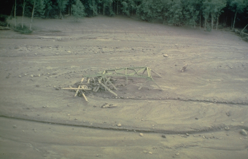 The twisted girders of a highway bridge within lahar deposits from Mount St. Helens. This 18 May 1980 mudflow was produced by dewatering (meltwater coming out) of the debris avalanche deposit in the North Fork Toutle River that traveled as far as the Columbia River, decreasing the depth of the navigational channel from 11 to 4 m. Photo by Dan Miller, 1980 (U.S. Geological Survey).