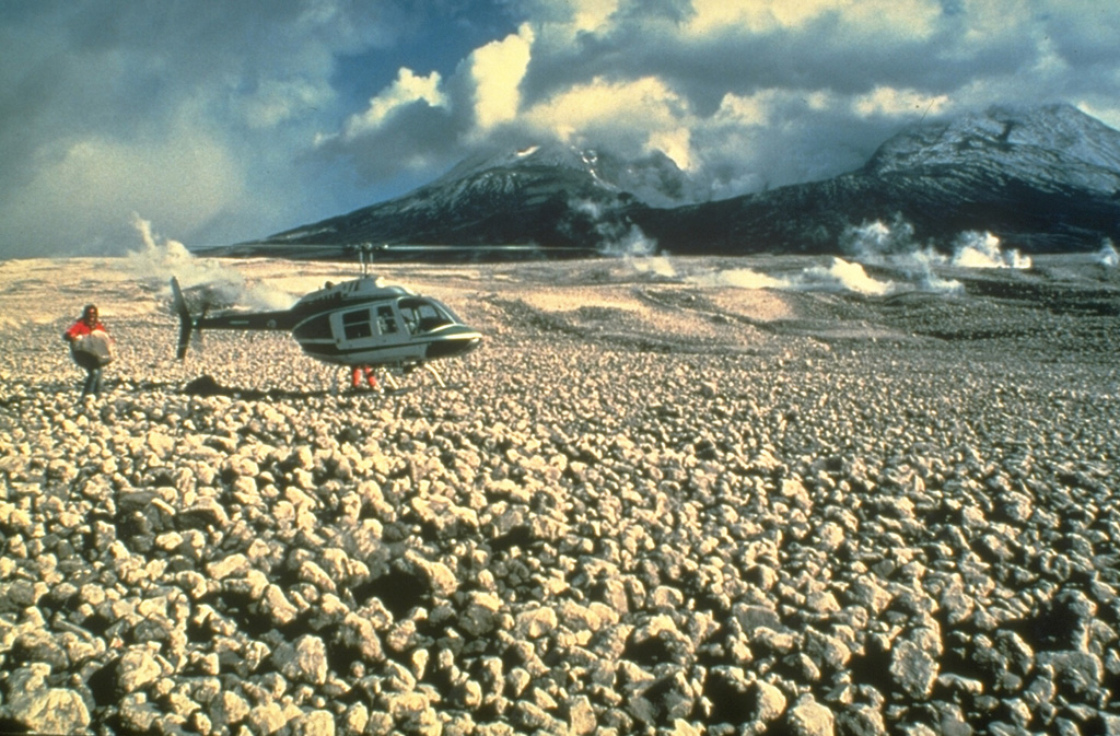 Pumice clasts from the 18 May 1980 eruption form the pumice plain immediately north of Mount St. Helens, shown in this 23 May photo. Pumiceous pyroclastic flows on 18 May traveled 8 km from the crater, as far as Spirit Lake. A geologist can be seen holding a large, light-weight block of pumice. Pumiceous pyroclastic flows were also erupted on 25 May, 12 June, 22 July, 7 August, and 16-18 October 1980. Photo by Dan Miller, 1980 (U.S. Geological Survey).