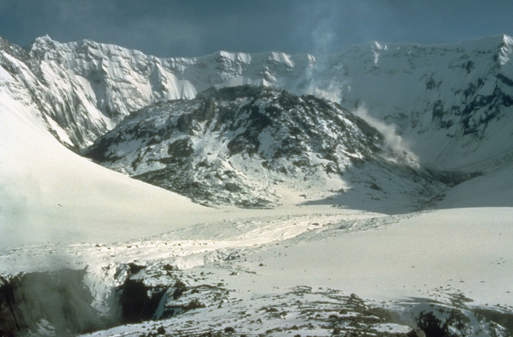 Four years after the powerful 18 May 1980 eruption of Mount St. Helens, a lava dome partially fills the crater. The dome, seen here from the north on 16 May 1984, grew during episodic periods of rapid growth that lasted from 1980 until 1986. By the end of the eruption the dome filled much of the crater floor, reaching a width of 1,100 m and a height of 250 m. Photo by Lyn Topinka, 1984 (U.S. Geological Survey).