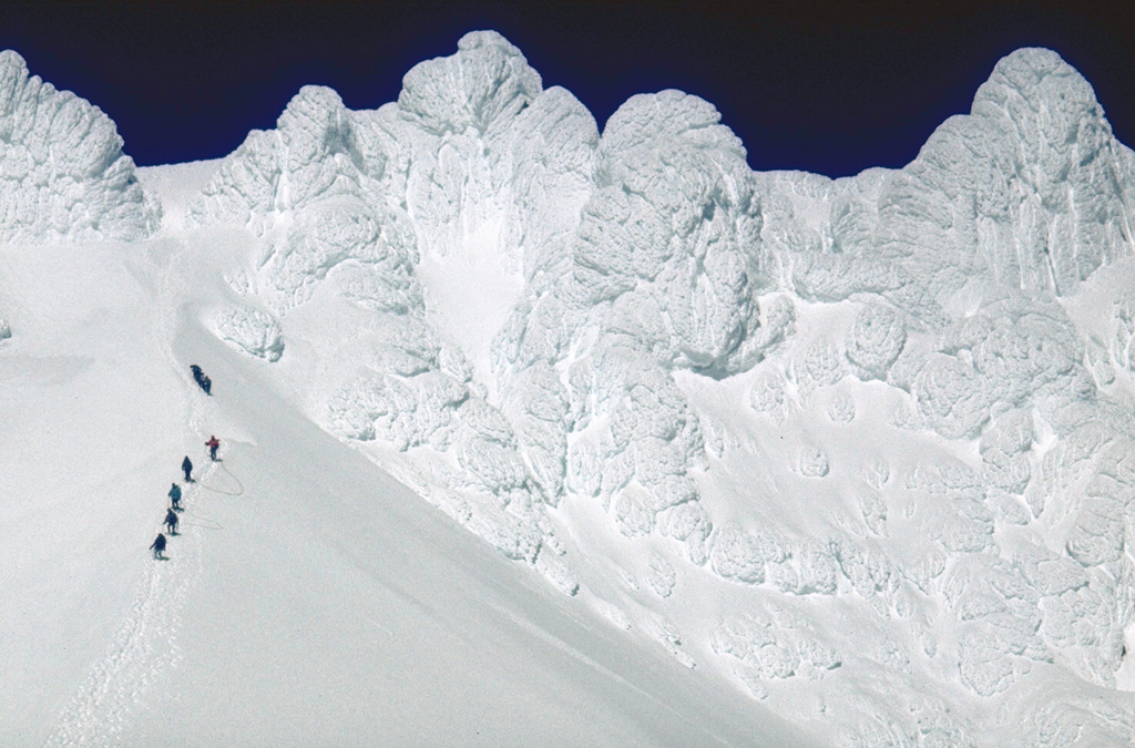 Oregon's Mount Hood is one of the most frequently climbed volcanoes in the Cascade Range. A group of climbers above the base of Crater Rock lava dome on the upper SW flank approaches Steel Cliffs that form the summit ridge. Photo by Lee Siebert, 1968 (Smithsonian Institution).