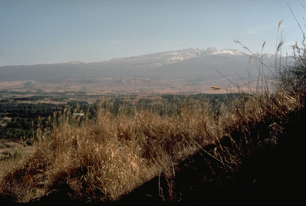 Snow-capped Halla shield volcano is seen here from the north, near Cheju city, the largest on Cheju Island. Voluminous lava flows and an underlying lava plateau form the entire 40 x 80 km island. The volcano is capped by the 400-m-wide Backlockdam summit crater and its flanks contain hundreds of cones, some of which form small offshore islands. Photo by Norm Banks, 1980 (U.S. Geological Survey).