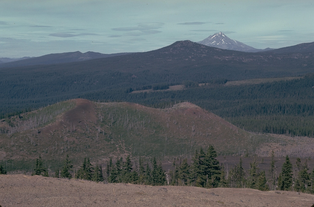 The Sand Mountain volcanic field contains a group of 23 scoria cones that erupted along a N-S line NW of Mount Washington. Two cone alignments diverge at the highest cone, Sand Mountain. This view looks along the NNE alignment with Mount Jefferson visible in the distance. The Sand Mountain cones and associated lava flows erupted between about 3,000 and 4,000 years ago. Photo by Lee Siebert, 1981 (Smithsonian Institution).