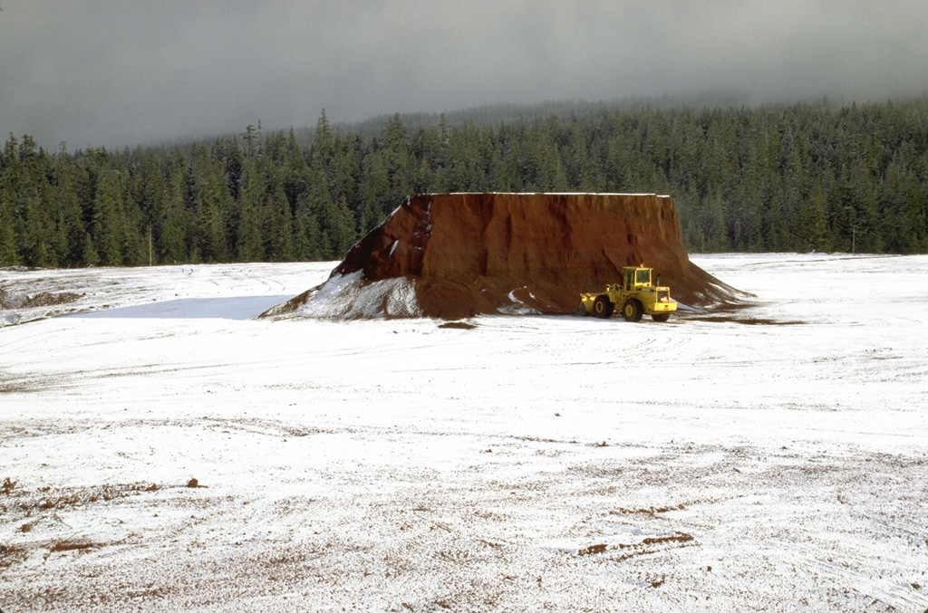 The flat summit of Little Nash Crater, a scoria cone of the Sand Mountain volcanic field in the central Oregon Cascades, has been extensively quarried to provide aggregate for highway construction. Red oxidized scoria from Little Nash Crater can be seen in road surfaces in the Santiam Pass area. Photo by Lee Siebert, 1995 (Smithsonian Institution).