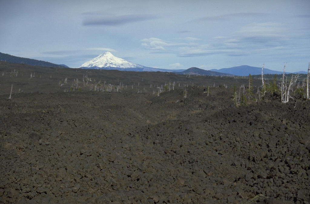The lava flow in the foreground, with snow-capped Mount Jefferson in the background, was emplaced about 2,600-2,900 years ago from Yapoah scoria cone on the north flank of North Sister. Lava flows in the middle of the photo originated from the Little Belknap shield volcano, part of one of the largest concentrations of recent volcanism in the continental United States: the McKenzie Pass area of the central Oregon Cascade Range. Photo by Lee Siebert, 1995 (Smithsonian Institution).