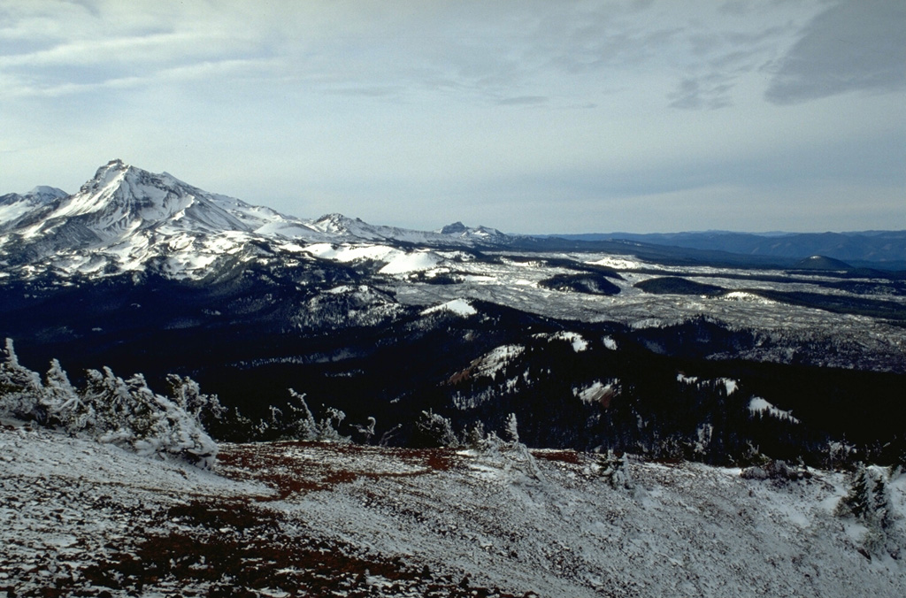 The north flank of North Sister contains young scoria cones that have produced lava flows during the past few thousand years, seen here covered with light snow. Yapoah cone, the symmetrical snow-covered cone in the center of the photo, produced a lava flow about 2,600-2,900 years ago that traveled beyond the margin of the photo for 13 km to the NE. Photo by Lee Siebert, 1995 (Smithsonian Institution).