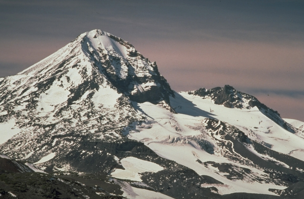 Middle Sister volcano, viewed from the west flank of Broken Top to the SE, has a smoother profile than North Sister volcano to the right but also shows evidence of glacial erosion on its eastern flank, exposing part of the dacitic lava dome that formed its central plug. Photo by Lyn Topinka, 1985 (U.S. Geological Survey).