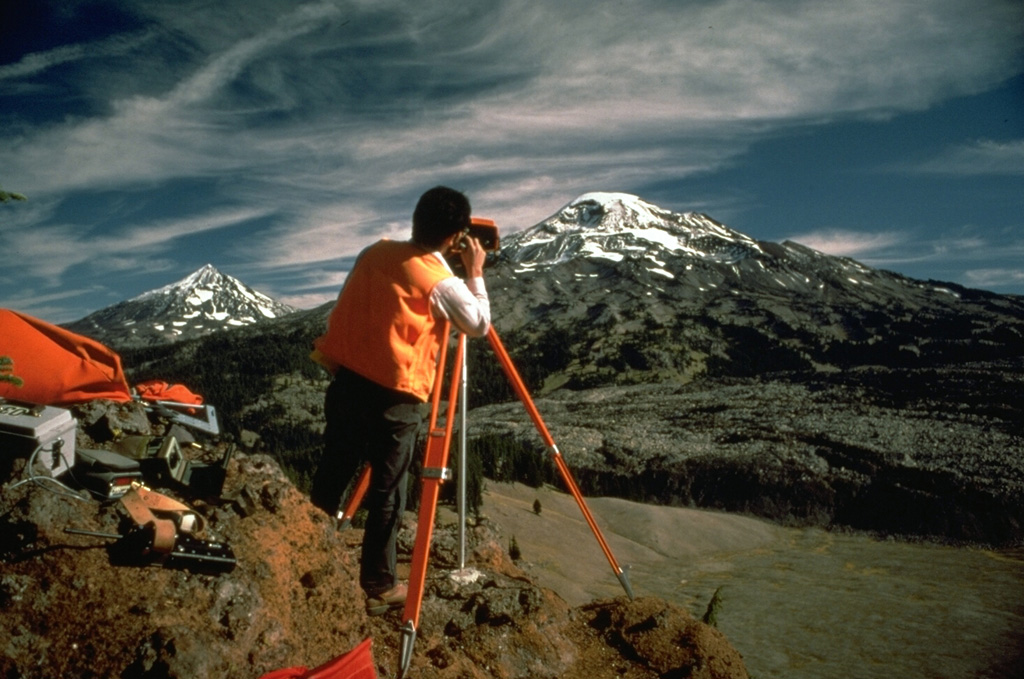 Electronic Distance Measurements (EDM) by the U.S. Geological Survey at South Sister volcano, with Middle Sister to the left, are conducted routinely to monitor these Cascades volcanoes for potential eruptive activity. By measuring the distance between two fixed points, these instruments can detect minor changes in the surface of the volcanic edifice that can occur prior to eruptions. Photo by Lyn Topinka, 1985 (U.S. Geological Survey).