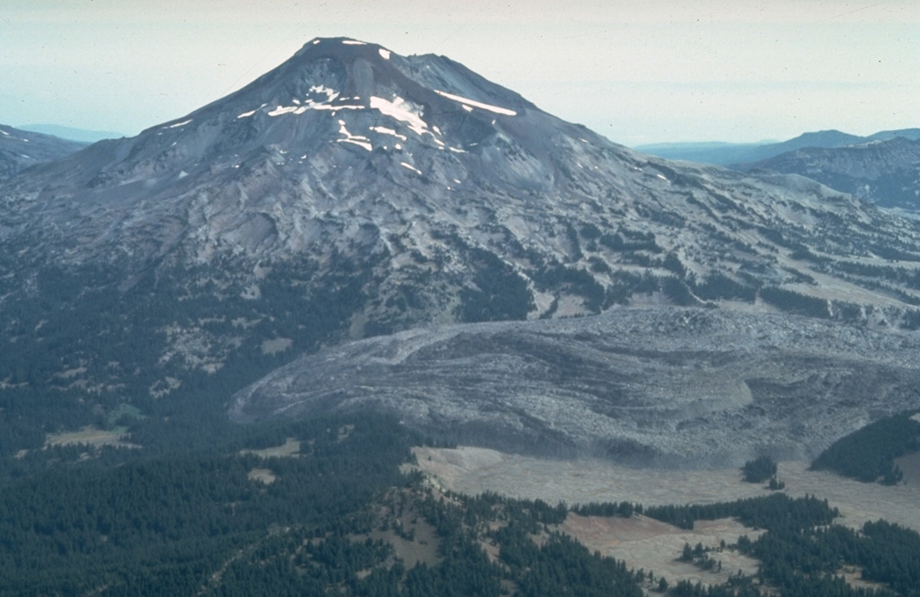 The large lava flow to the lower right is the Rock Mesa lava flow on the SW flank of South Sister. The rhyodacite flow erupted about 2,300 years ago from a vent now filled by a small lava dome. Lava extrusion was preceded by explosive eruptions that produced airfall tephra and pyroclastic flows.  Photo by Willie Scott, 1981 (U.S. Geological Survey).