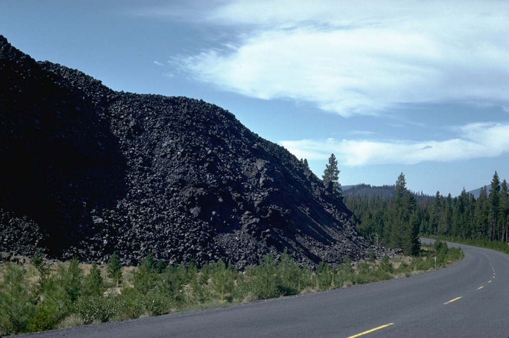 The steep margin of a lava flow from a scoria cone at the northern end of Davis Lake is skirted by a road in Deschutes National Forest. This and two other nearby lava flows mark the Holocene eruptive activity in the Cascades between Mount Bachelor and Crater Lake. Photo by Lee Siebert, 1982 (Smithsonian Institution).
