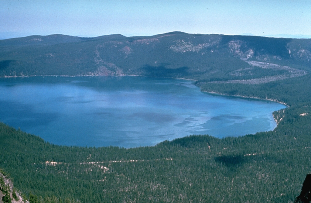 Paulina Lake is the westernmost of two lakes within Newberry caldera and is seen here from Paulina Peak, the high point of the southern caldera rim. The lava flow entering the lake to the upper right erupted about 6,400 years ago from the Central Pumice Cone. The flow split into two lobes, and the other lobe traveled into East Lake, just out of view to the right. This was one of several eruptive vents within the caldera that were active during this eruptive phase. Photo by Willie Scott, 1974 (U.S. Geological Survey).