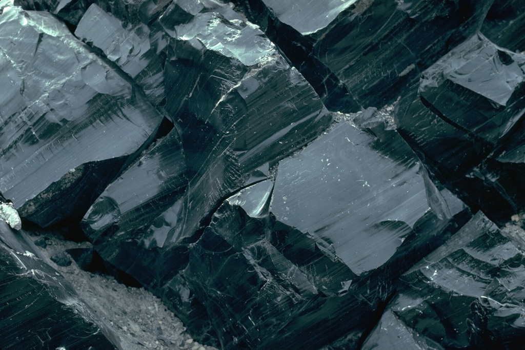 The Big Obsidian Flow erupted from Newberry caldera in central Oregon is composed of glassy rhyolite, formed when lava rapidly cools. The flow covers 20 km2 of the caldera floor. Obsidian flows are never entirely glassy, but also contain large amounts of frothy pumiceous material and devitrified (crystallized) spherulites, which commonly form bands alternating with layers of glass. Photo by Lee Siebert, 1981 (Smithsonian Institution).