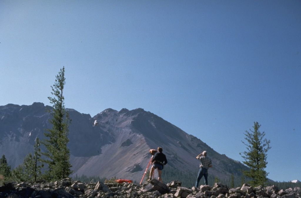 U.S. Geological Survey volcanologists conduct Electronic Distance Measurement surveys NW of Lassen Peak as part of a monitoring program at Lassen volcano.  Chaos Crags lava dome rises in the background.  The large scarp at the left was formed during collapse of part of Chaos Crags about 1650 CE. Photo by Lyn Topinka, 1984 (U.S. Geological Survey).