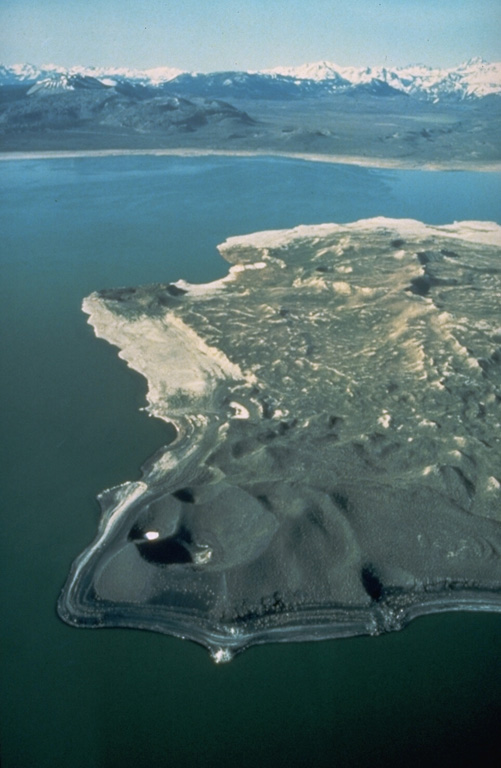 The Mono Lake volcanic field consists of rhyolitic lava domes and flows, phreatic explosion craters, and cinder cones on islands in Mono Lake and on its northern shore.  This view shows explosion craters on Paoha Island, with the Mono Craters dome complex and the Sierra Nevada in the distance to the south.  The ages of the most recent eruptions of the Mono Lake volcanic field range from about 2000 to about 200 years. Photo by Dan Dzurisin, 1983 (U.S. Geological Survey).