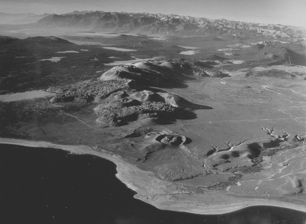 The Mono Craters volcanic field, between Mono Lake in the foreground and Long Valley caldera at the upper left, is a 17-km-long chain of rhyolitic lava domes and thick, viscous lava flows.  Mono Craters have been frequently active during the Holocene.  Panum crater (the vent nearest to Mono Lake), is partially filled by a lava dome and was the site of the latest eruption from Mono Craters, about 600 years ago.  Photo by R. Von Huene, 1971 (U.S. Geological Survey).