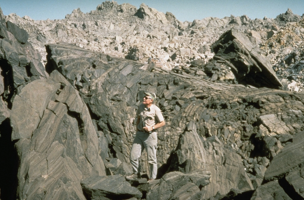 The Obsidian Flow, a lava flow with a hackly surface showing prominent flow banding, was erupted at the northern end of a chain of lava domes and flows during a dike-fed eruption about 600 years ago at Inyo Craters.  The Obsidian Flow was the largest of four flows and domes emplaced during this eruption. Photo by Larry Mastin, 1992 (U.S. Geological Survey).