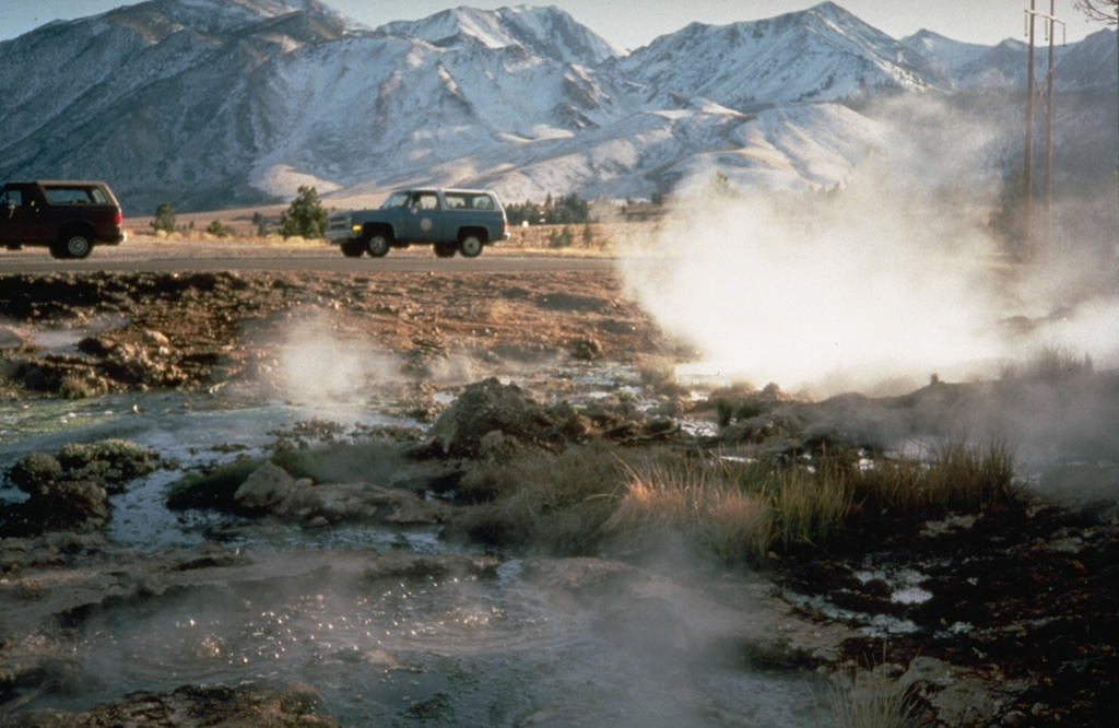 Steam rises from hot springs on the floor of the Long Valley caldera.  Hot springs, fumaroles and active hydrothermal alteration are found throughout much of the caldera, but are particularly prevalent in the SE caldera moat area and on the flanks of the resurgent dome.  The Sierra Nevada Range towers above the SW caldera margin in the background. Photo by Larry Mastin, 1991 (U.S. Geological Survey).