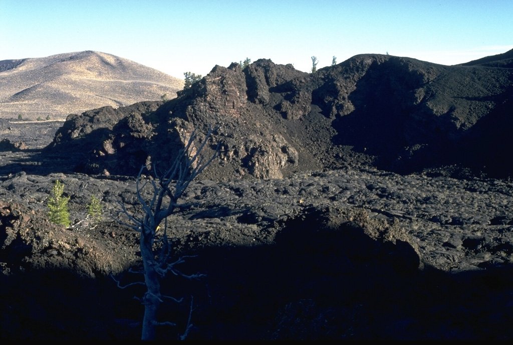 The Big Craters lava flow in the foreground, one of the youngest at the Craters of the Moon, originated about 2200 years ago from vents at the northern base of Big Craters.  The flows traveled north before being deflected by the slopes of the Pioneer Mountains in the background and then flowed primarily to the SW. Photo by Lee Siebert, 1994 (Smithsonian Institution).