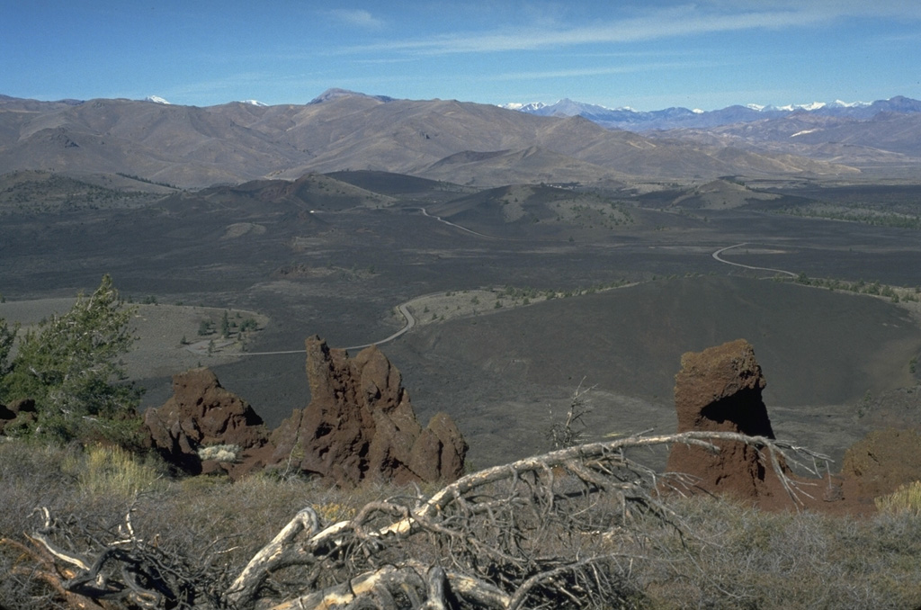 The Craters of the Moon lava field covers 1600 km2 of the Snake River Plain with lava flows erupted from NW-SE-trending fissures and cinder cones.  The northern part of the lava field, seen from Big Cinder Butte with the Pioneer Mountains in the background to the north, contains many flows and cinder cones formed during the most recent eruptions about 2300 to 2100 years ago. Photo by Lee Siebert, 1994 (Smithsonian Institution).