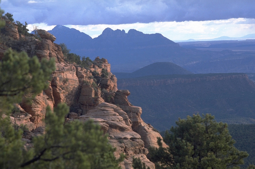 The cinder cone at the right center is Crater Hill, the southernmost and youngest feature of the Kolob volcanic field, a line of cinder cones near the western margin of Zion National Park. Cross-bedded sandstones of the Jurassic-age Navajo Sandstone form the cliffs in the foreground. Photo by Lee Siebert, 1987 (Smithsonian Institution).