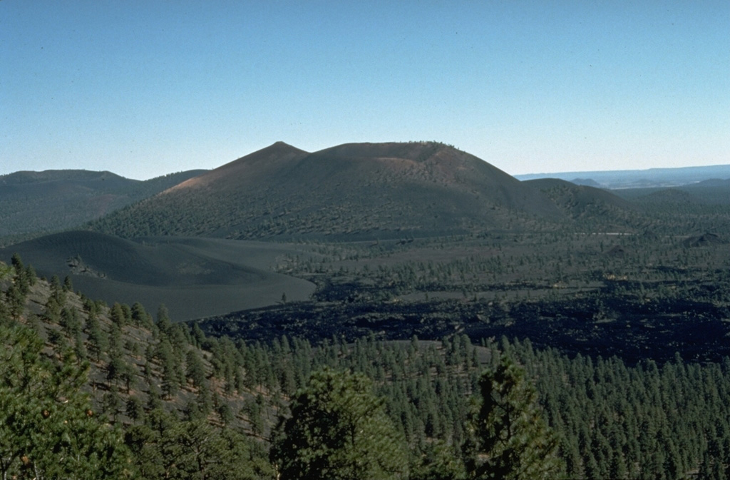 The Bonita lava flow in the foreground of this view from O'Leary Peak, NW of Sunset Crater, was erupted from two or more vents on the western to NW flank of Sunset Crater.  The flow contains both scoria-mantled portions erupted concurrently with major explosive activity from Sunset Crater and darker, scoria-free portions erupted during later stages of the eruption.  Portions of the scoria-mantled flow were broken away and rafted along during the late-stage lava extrusion. Photo by Ed Wolfe, 1977 (U.S. Geological Survey).