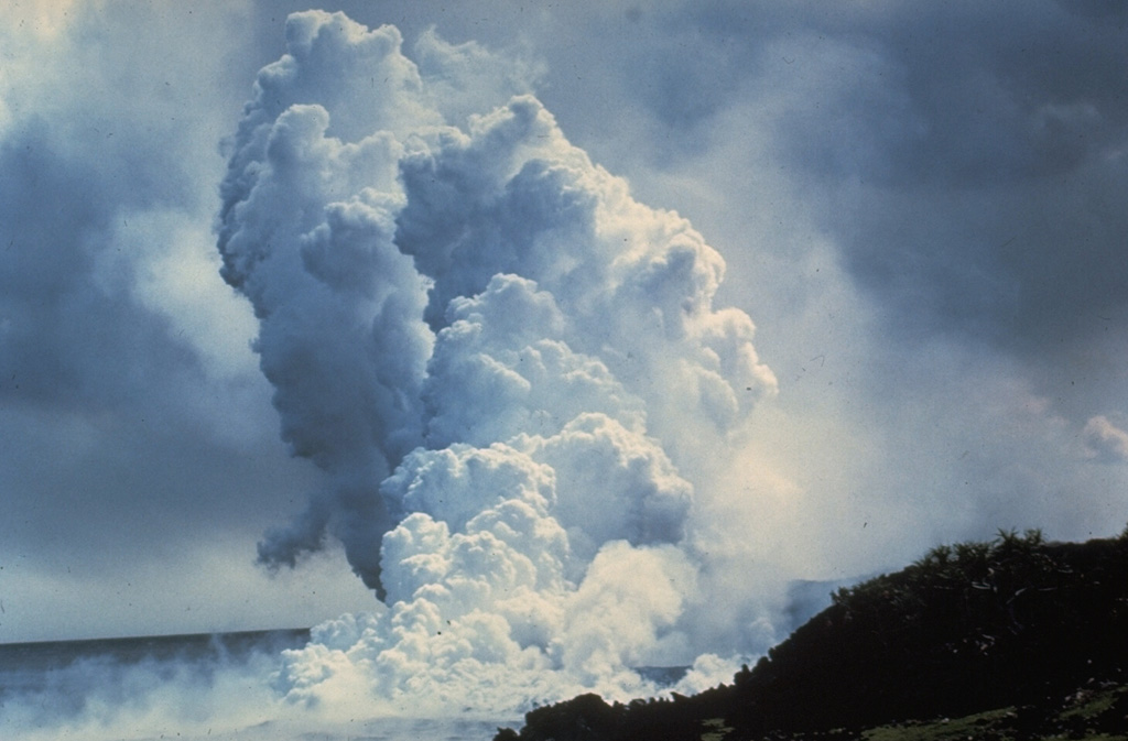 A laze plume (hydrochloric acid, steam, and fine glass particles) rises from a lava flow entering the sea on 28 March 1955. The eruption began on 28 February and formed 24 vents across 15 km on the lower East Rift Zone. Three lava flows reached the sea, and a fourth flow stopped just short of the Puna coast near the eastern tip of the Island of Hawaii. The eruption lasted 88 days, ending on 26 May. Photo by Jerry Eaton, 1955 (U.S. Geological Survey).