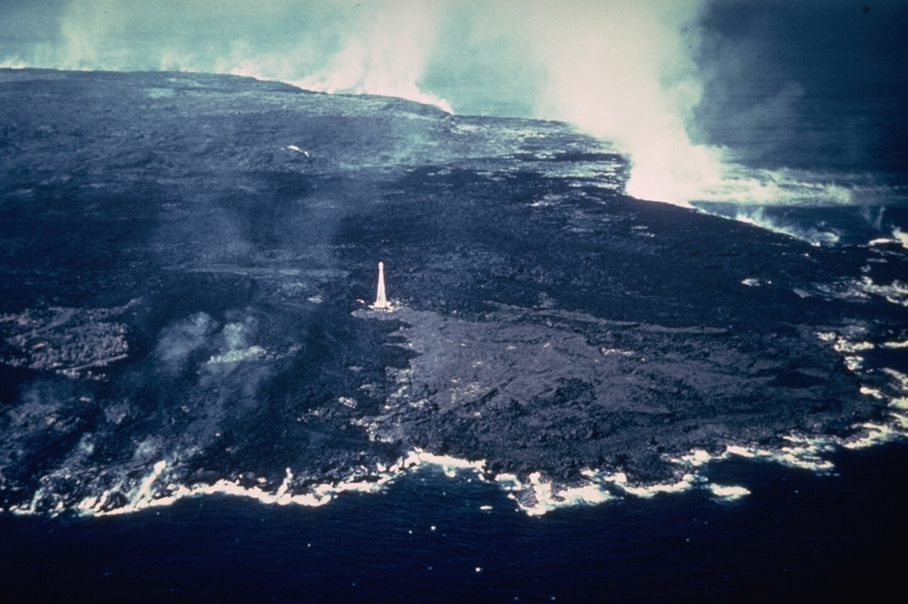 An aerial view from the SE on 11 February 1960 shows steam rising from Kilauea lava flows that reached the coast. The lava flows extended the shoreline at the NE tip of the island of Hawaii up to nearly 1 km along a 5-km-long front. The entire area of this photo, with the exception of the wedge-shaped lighter-gray area extending to the coast from the Cape Kumukahi lighthouse, was inundated by 1960 lava flows. The eruption ended eight days after this photo was taken. Photo by Hawaii Volcanoes National Park, 1960.