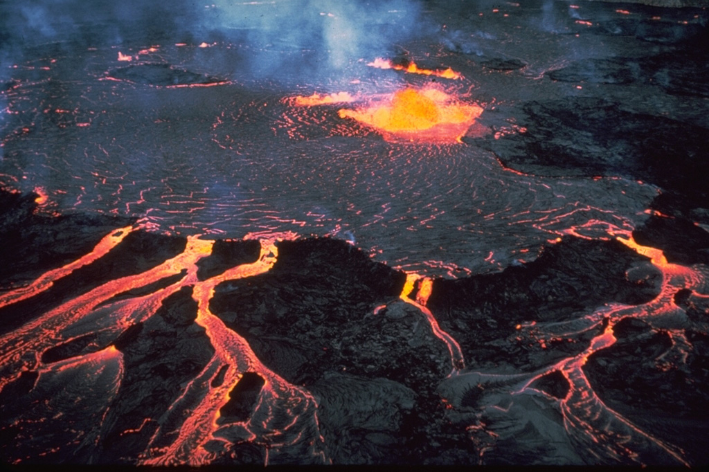 This January 1968 photo of Halema‘uma‘u crater shows lava fountaining within the partly solidified crust of lava lake, and also overflowing below. This eruption began on 5 November 1967 and lasted until 13 July 1968. Photo by Richard Fiske, 1968 (Smithsonian Institution).