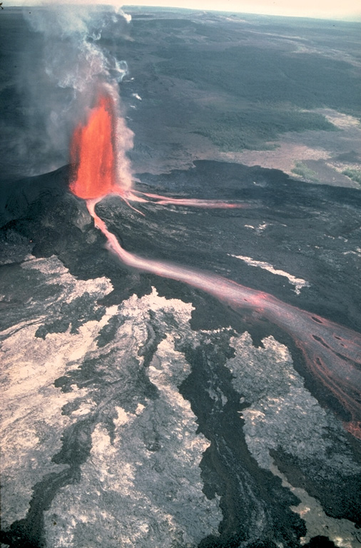 This tall lava fountain erupted from Pu‘u ‘Ō‘ō vent at Kilauea on 30 June 1984, producing incandescent lava flows. An eruption on the East Rift Zone began on 3 January 1983, and with short interruptions remained active through to September 2018. Eruptions initially occurred in the Pu‘u ‘Ō‘ō area, but activity shifted to various locations on the East Rift Zone, including the Kūpaianaha vent 3 km farther down the rift. An extensive lava flow field formed between the east rift and the coast. Photo by J.D. Griggs, 1984 (U.S. Geological Survey).