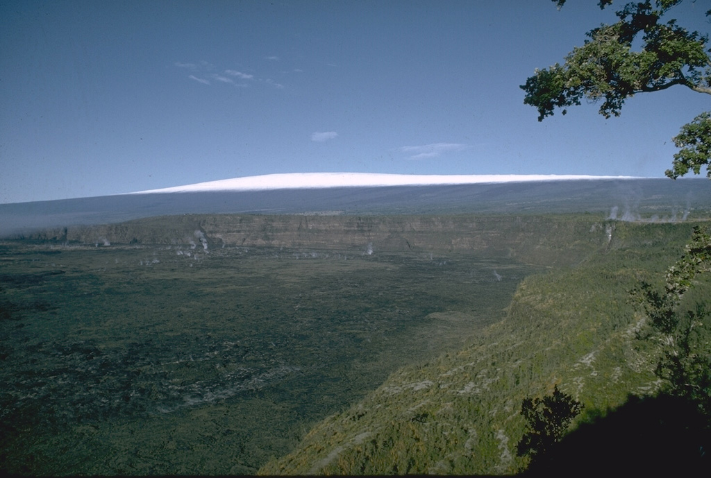 The 3 x 5 km caldera at the summit of Kilauea is home of the Goddess Pele and has been Hawaii's most active volcano during historical time. Kilauea is a shield volcano on the east flank of Mauna Loa, visible in the distance. Eruptions originate both from within the summit caldera and from SW and E rift zones that extend to the sea and predominately produce lava flows, with occasional explosive eruptions. Photo by Richard Fiske, 1967 (Smithsonian Institution).