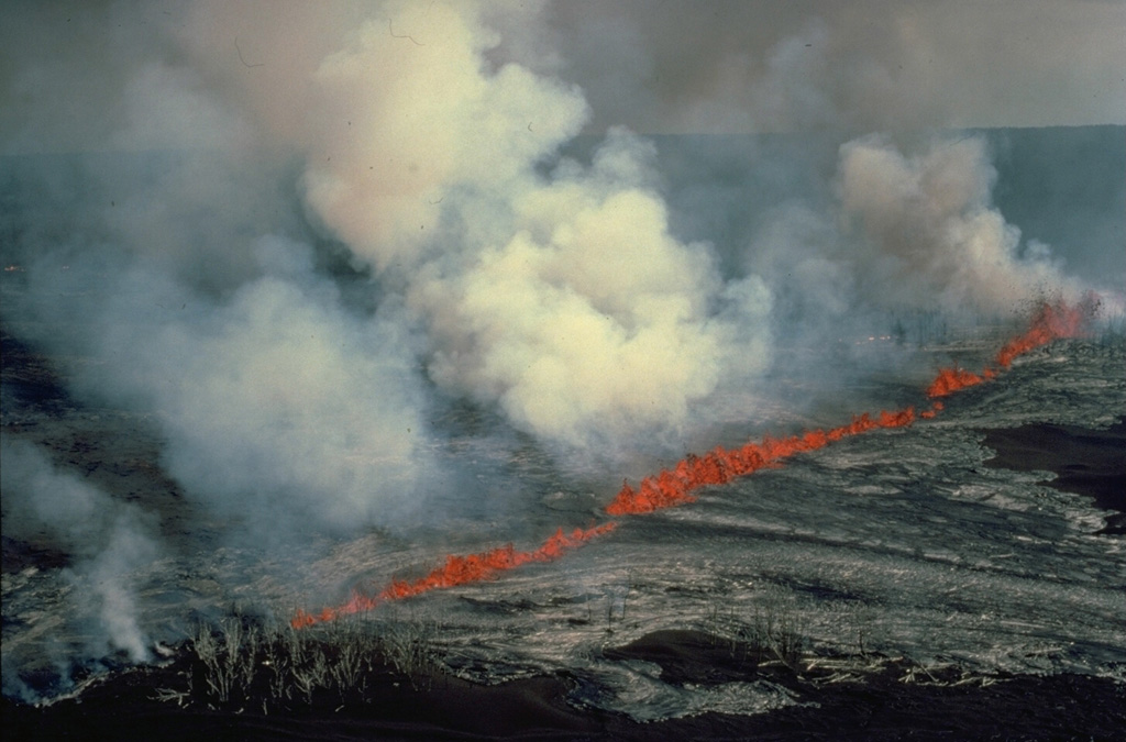 Many volcanic eruptions originate from fractures that reach the Earth's surface.  Eruptive fissures, such as producing this curtain of fire along the east rift zone of Kilauea volcano in July 1986, often extend radially away from the summit of a volcano.  Light-colored lava flows fed by the lava fountains move downslope on both sides of the fissure.  At some volcanoes fissures follow the direction of regional faults, and circumferential fissures can open around the rim of a volcanic caldera.      Copyrighted photo by Katia and Maurice Krafft, 1986.